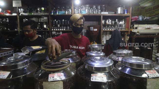 Pekerja menyortir biji kopi di salah satu gerai penjual biji kopi di Pasar Santa, Jakarta, Rabu (3/3/2021). [Suara.com/Angga Budhiyanto]