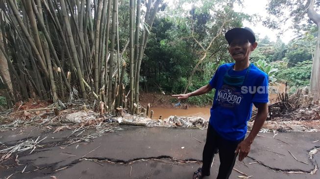 Ketua RT 04 RT 06 Kelurahan Cirendeu, Ciputat Timur, Tangsel, Akhyaruddin menunjukkan Jalan Lembah 1 yang retak dan longsor, Selasa (2/3/2021). [Suara.com/Wivy]