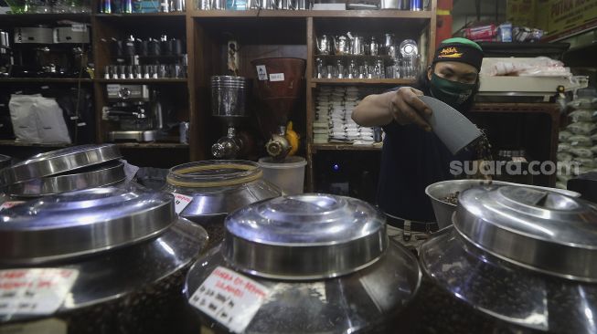 Pekerja menyortir biji kopi di salah satu gerai penjual biji kopi di Pasar Santa, Jakarta, Rabu (3/3/2021). [Suara.com/Angga Budhiyanto]