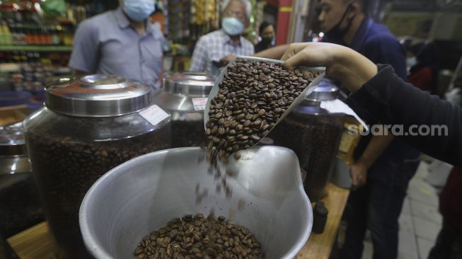 Pekerja menyortir biji kopi di salah satu gerai penjual biji kopi di Pasar Santa, Jakarta, Rabu (3/3/2021). [Suara.com/Angga Budhiyanto]