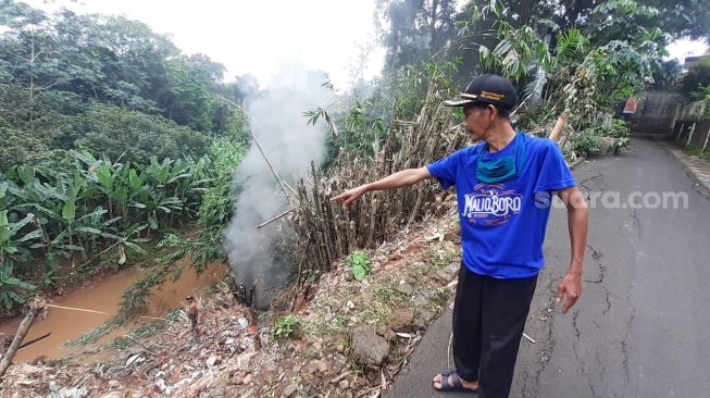 Ketua RT 04 RT 06 Kelurahan Cirendeu, Ciputat Timur, Tangsel, Akhyaruddin menunjukkan Jalan Lembah 1 yang retak dan longsor, Selasa (2/3/2021). [Suara.com/Wivy]