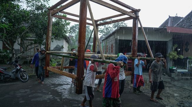 Sejumlah warga mengangkat rangka rumah kayu di Wedomartani, Ngemplak, Sleman, DI Yogyakarta, Rabu (3/3/2021).  ANTARA FOTO/Hendra Nurdiyansyah