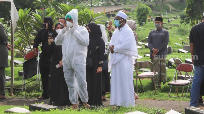 Suami mendiang Presenter Rina Gunawan, Teddy Syah mengenakan pakaian APD untuk melaksanakan prosesi pemakaman sang istri di TPU Tanah Kusir, Jakarta Selatan, Rabu (3/3/2021). [Suara.com/Alfian Winanto]