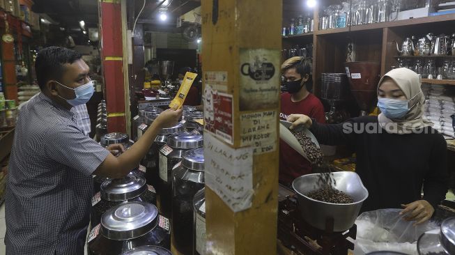 Penjual biji kopi melayani pembeli di salah satu gerai penjual biji kopi di Pasar Santa, Jakarta, Rabu (3/3/2021). [Suara.com/Angga Budhiyanto]