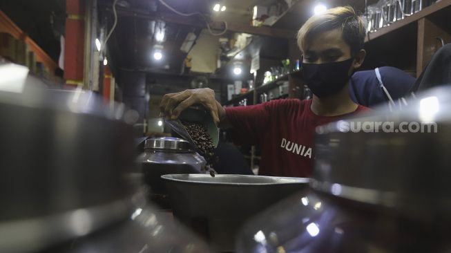 Pekerja menyortir biji kopi di salah satu gerai penjual biji kopi di Pasar Santa, Jakarta, Rabu (3/3/2021). [Suara.com/Angga Budhiyanto]