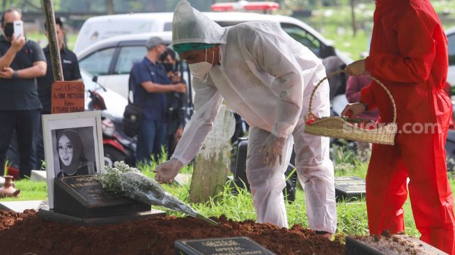 Suami mendiang Presenter Rina Gunawan, Teddy Syah menaruh bunga di atas pusara sang istri saat prosesi pemakaman di TPU Tanah Kusir, Jakarta Selatan, Rabu (3/3/2021). [Suara.com/Alfian Winanto]