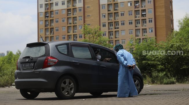 Petugas kesehatan melayani warga yang berada di atas kendaraan usai melakukan vaksinasi COVID-19 dengan sistem 'drive thru' di area parkir Hall C JIExpo Kemayoran, Jakarta, Rabu (3/3/2021). [Suara.com/Angga Budhiyanto]