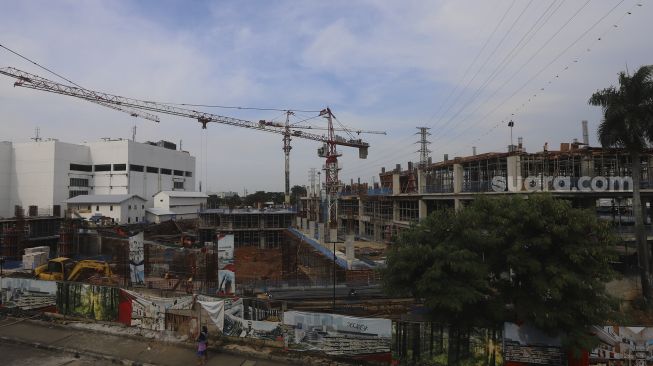 Pekerja dibantu alat berat menyelesaikan pembangunan Pasar Senen Jaya Blok I dan II, Jakarta, Kamis (4/3/2021). [Suara.com/Angga Budhiyanto]