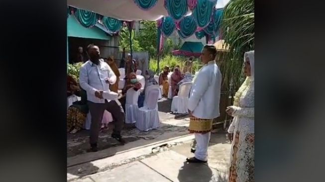 Emak-emak santuy lewat saat pengantin difoto. (TikTok/@bayu__firmasnyah)