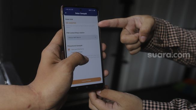 Petugas menunjukkan aplikasi di drop point rekosistem yang berada di Stasiun MRT Blok M, Jakarta, Jumat (5/3/2021). [Suara.com/Angga Budhiyanto]