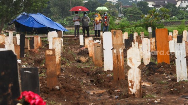 Warga berziarah ke makam kerabatnya di area khusus pemakaman Covid-19 yang terisi penuh di TPU Bambu Apus , Jakarta Timur, Sabtu (6/3/2021). [Suara.com/Alfian Winanto]