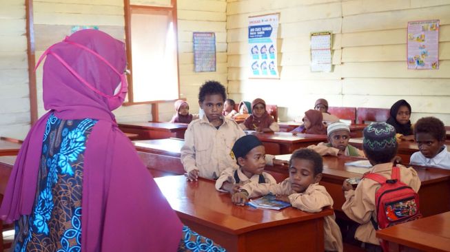 Seorang guru dengan masker di wajahnya mengajar sejumlah murid yang tidak menggunakan masker di SD Al Maarif 1 Kampung Maibo, Kabupaten Sorong, Papua Barat, Sabtu (6/3/2021).  ANTARA FOTO/Olha Mulalinda