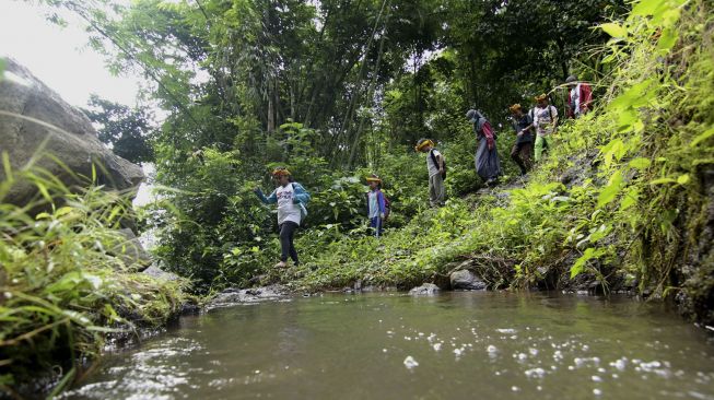 Anak-anak melintasi sungai dalam pembelajaran Jelajah Rimba Sekolah Alam Kampung Baca Taman Rimba (Batara) di Papring, Kalipuro, Banyuwangi, Jawa Timur, Minggu (7/3/2021). [ANTARA FOTO/Budi Candra Setya]