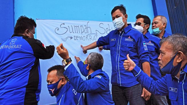 Sejumlah kader Partai Demokrat daerah Banten membubuhkan tanda tangan dan cap jempol darah pada kain putih saat Aksi Solidaritas Kader Partai Demokrat Tolak Kongres Luar Biasa Deli Serdang di Serang, Banten, Senin (8/3/2021). ANTARA FOTO/Asep Fathulrahman