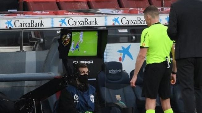 Wasit Alejandro Hernandez Hernandez sedang memperhatikan rekaman ulang pertandingan di layar VAR. [AFP] 