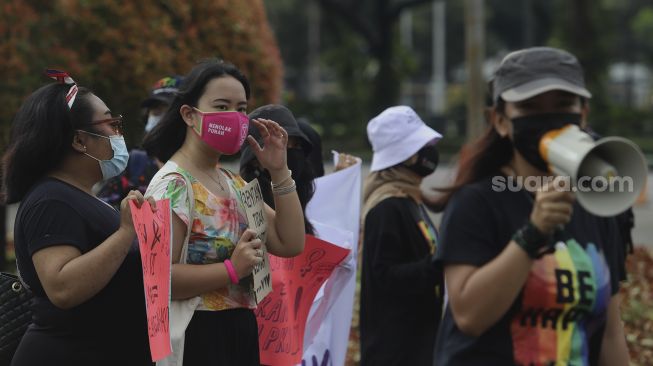 Sejumlah massa yang tergabung dalam Perempuan Mahardhika membawa poster saat melakukan aksi memperingati Hari Perempuan Internasional di kawasan Patung Kuda Arjuna Wiwaha, Jakarta, Senin (8/3/2021). [Suara.com/Angga Budhiyanto]