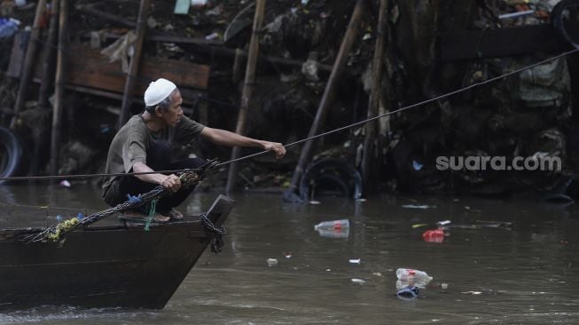 Seorang warga mengoperasikan perahu eretan untuk menyeberangi Kali Ciliwung di kawasan Manggarai, Jakarta, Selasa (9/3/2021). [Suara.com/Angga Budhiyanto]