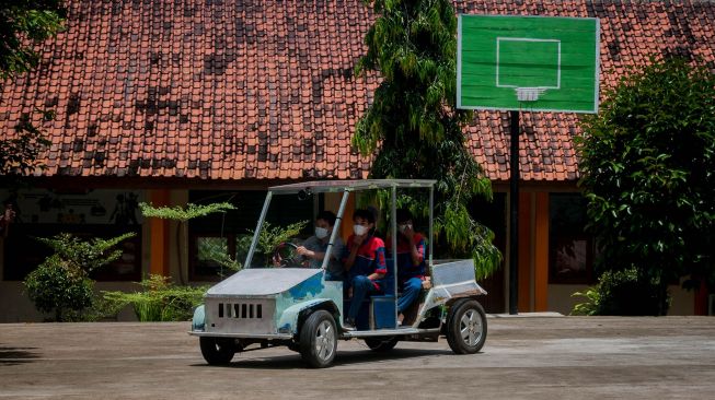 Pelajar didampingi gurunya melakukan uji coba berkendara mobil listrik di SMKN 4 Pandeglang, Banten, Selasa (9/3/2021). ANTARA FOTO/Muhammad Bagus Khoirunas
