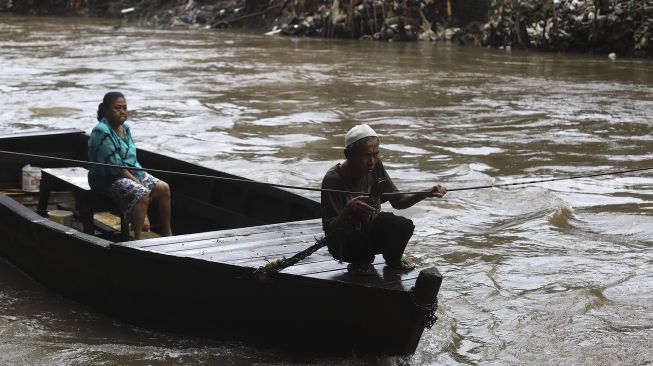 Warga menaiki perahu eretan untuk menyeberangi Kali Ciliwung di kawasan Manggarai, Jakarta, Selasa (9/3/2021). [Suara.com/Angga Budhiyanto]