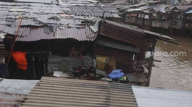 Seorang warga beraktivitas di permukiman bantaran Kali Ciliwung, kawasan Manggarai, Jakarta, Selasa (9/3/2021). [Suara.com/Angga Budhiyanto]