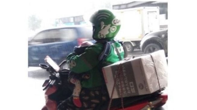 Potret Ojol Gendong Anak sambil Berteduh: Superhero Sesungguhnya