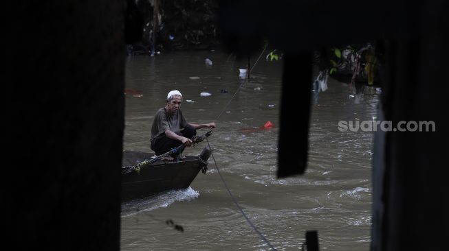 Seorang warga mengoperasikan perahu eretan untuk menyeberangi Kali Ciliwung di kawasan Manggarai, Jakarta, Selasa (9/3/2021). [Suara.com/Angga Budhiyanto]