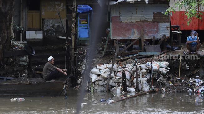 Seorang warga mengoperasikan perahu eretan untuk menyeberangi Kali Ciliwung di kawasan Manggarai, Jakarta, Selasa (9/3/2021). [Suara.com/Angga Budhiyanto]