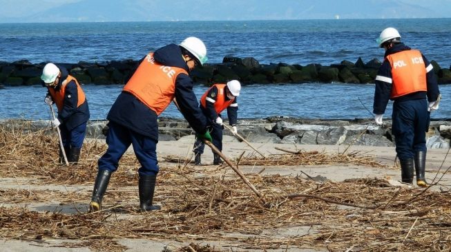 Petugas membersihkan lokasi tsunami Jepang 2011. [STR / JIJI PRESS / AFP]