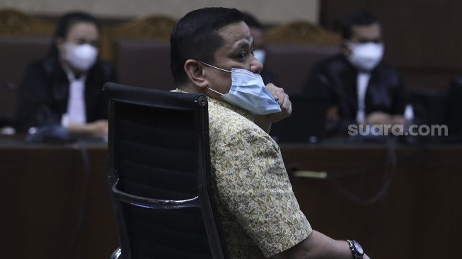 Terdakwa kasus suap penghapusan red notice Djoko Tjandra, Irjen Pol Napoleon Bonaparte membetulkan masker yang dikenakannya saat menjalani sidang dengan agenda pembacaan putusan di Pengadilan Tipikor, Jakarta, Rabu (10/3/2021). [Suara.com/Angga Budhiyanto]