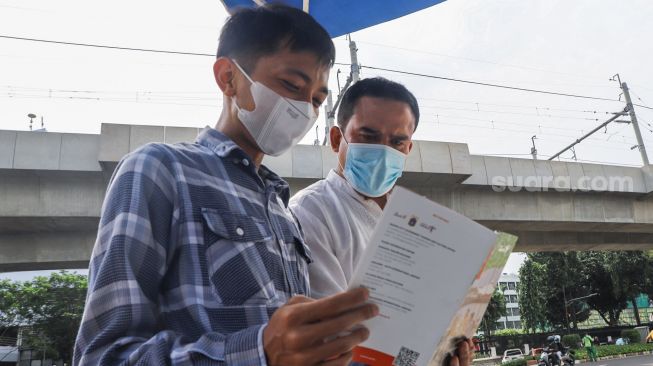 Petugas Dinas Pariwisata dan Ekonomi Kreatif DKI Jakarta menjelaskan tentang destinasi wisata kepada warga saat uji coba Tourist Information Center Mobile (TICM) di Terminal Blok M, Jakarta Selatan, Jumat (12/3/2021). [Suara.com/Alfian Winanto]