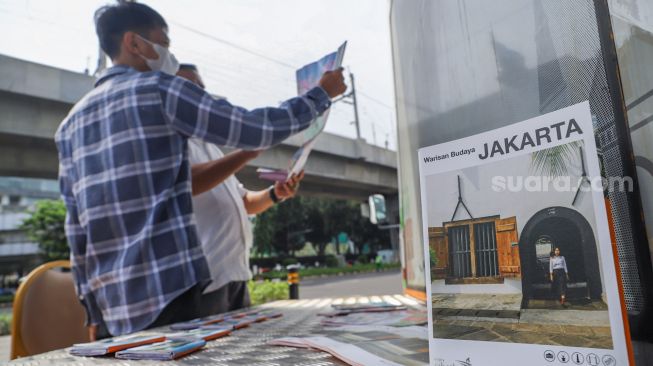 Petugas Dinas Pariwisata dan Ekonomi Kreatif DKI Jakarta menjelaskan tentang destinasi wisata kepada warga saat uji coba Tourist Information Center Mobile (TICM) di Terminal Blok M, Jakarta Selatan, Jumat (12/3/2021). [Suara.com/Alfian Winanto]
