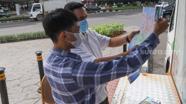 Petugas Dinas Pariwisata dan Ekonomi Kreatif DKI Jakarta menjelaskan tentang destinasi wisata kepada warga saat uji coba Tourist Information Center Mobile (TICM) di Terminal Blok M, Jakarta Selatan, Jumat (12/3/2021). [Suara.com/Alfian Winanto]