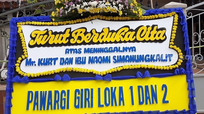 Karangan bunga duka cita atas meninggalnya pasangan suami istri (pasutri) yang jadi korban pembacokan dan pembunuhan di kediaman mereka di  Perumahan Giriloka 2 Kelurahan Lengkong Wetan, Kecamatan Serpong, Tangsel, Sabtu (13/3/2021). [Suara.com/Wivy]