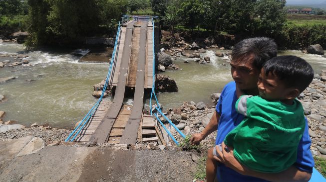 Warga mengamati jembatan rusak di Desa Kweden, Nganjuk, Jawa Timur, Sabtu (13/3/2021). ANTARA FOTO/Prasetia Fauzani