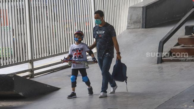 Orang tua mengajak anaknya untuk bermain skateboard di arena Skatepark Pasar Rebo, Jakarta Timur, Sabtu (13/3/2021). [Suara.com/Alfian Winanto]