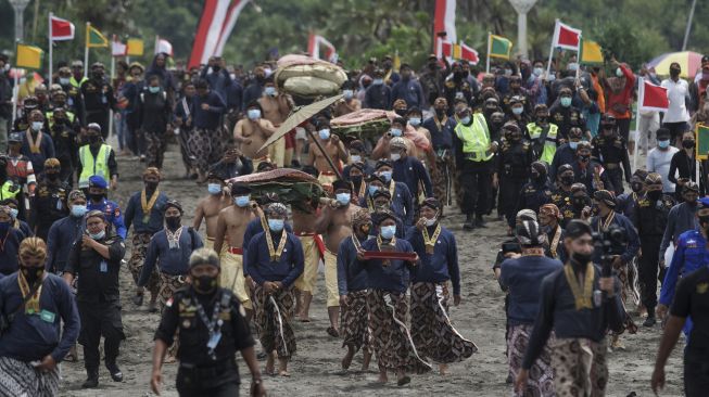 Sejumlah abdi dalem Keraton Yogyakarta membawa sesaji menuju pantai saat Prosesi Labuhan Parangkusumo di Pantai Parang Kusumo, Bantul, DI Yogyakarta, Minggu (14/3/2021). [ANTARA FOTO/Andreas Fitri Atmoko]