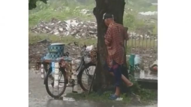 Berteduh di Bawah Pohon Demi Dagangan saat Hujan, Bapak Ini Bikin Terenyuh