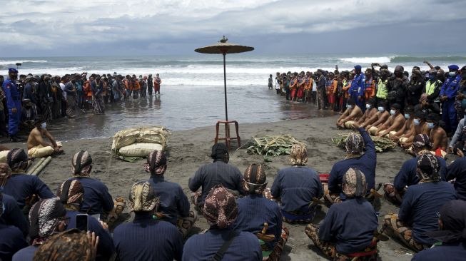 Sejumlah abdi dalem Keraton Yogyakarta berdoa di bibir pantai saat Prosesi Labuhan Parangkusumo di Pantai Parang Kusumo, Bantul, DI Yogyakarta, Minggu (14/3/2021). [ANTARA FOTO/Andreas Fitri Atmoko]