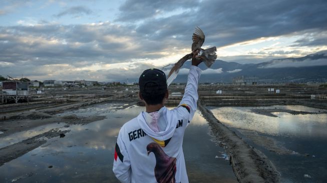 Seorang peserta bersiap menerbangkan burung merpatinya pada Lomba Merpati Balap di Palu, Sulawesi Tengah, Minggu (14/3/2021). [ANTARA FOTO/Basri Marzuki]