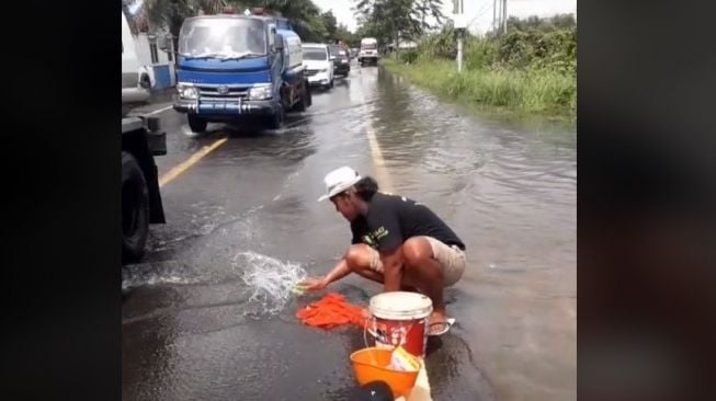 Aksi pria mencuci baju di jalan raya mendapat sorotan dari warganet (TikTok)