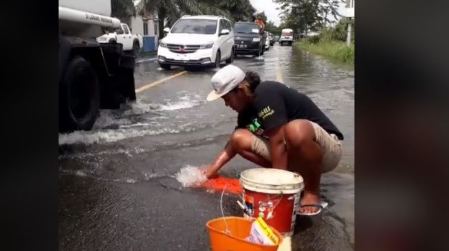 Bukan di Sungai, Pria Ini Pilih Jalan Raya sebagai Tempat Cuci Baju