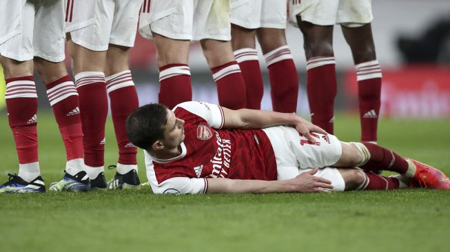 Bek Arsenal, Cedric Soares berbaring di lantai di bawah tembok pertahanan saat Tottenham Hotspur melakukan tendangan bebas ke gawang selama pertandingan sepak bola Liga Inggris antara Arsenal dan Tottenham Hotspur di Emirates Stadium, London, pada (14/3/2021). [Nick Potts / POOL / AFP]