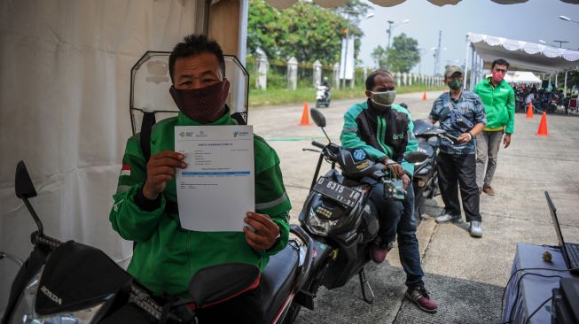 Pengemudi ojek daring menunjukan sertifikat setelah menjalani vaksinasi COVID-19 dengan layaran tanpa turun di Sport Center Arcamanik, Bandung, Jawa Barat, Selasa (16/3/2021). [ANTARA FOTO/Raisan Al Farisi]