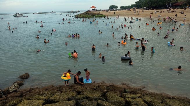 Wisatawan lokal menikmati suasana saat liburan di Pantai Sanur, Denpasar, Bali, Senin (15/3/2021).  ANTARA FOTO/Nyoman Hendra Wibowo