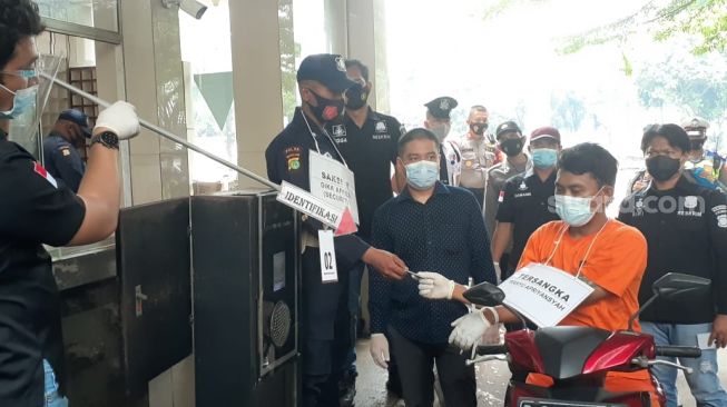 Pelaku pembunuhan WN Jerman dan istrinya, Wahyu Apriansyah melakukan rekonstruksi saat adegan memberikan SIM kepada satpam sebelum masuk ke Perumahan Giri Loka 2, Serpong, Tangsel, Kamis (18/3/2021). [Suara.com/Wivy]