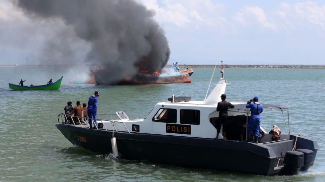 Petugas dari Kejaksaan Negeri Banda Aceh, Pengawasan Sumber Daya Kelautan dan Perikanan (PSDKP) dan personel Dit Pol Air Polda Aceh mengawasi jalannya eksekusi pemusnahan kapal penangkap ikan negara asing berbendera Malaysia di perairan Pelabuhan Samudera Lampulo, Banda Aceh, Aceh, Kamis (18/3/2021).  ANTARA FOTO/Irwansyah Putra