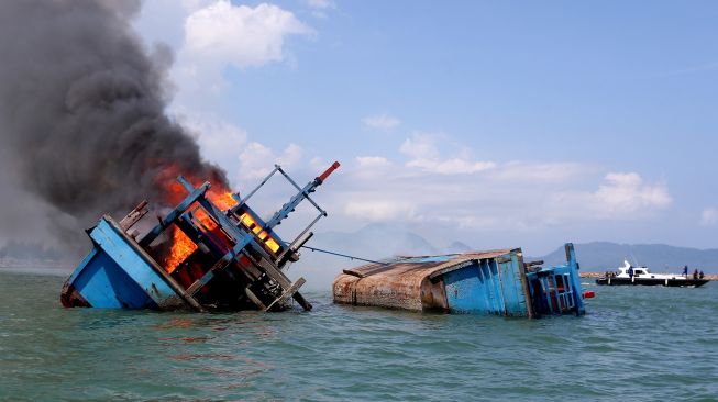 Petugas mengawasi jalannya eksekusi pemusnahan kapal penangkap ikan negara asing berbendera Malaysia di perairan Pelabuhan Samudera Lampulo, Banda Aceh, Aceh, Kamis (18/3/2021).  ANTARA FOTO/Irwansyah Putra