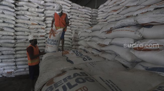 Pekerja menata karung berisi beras di Gudang Bulog Kanwil DKI dan Banten, Kelapa Gading, Jakarta, Kamis (18/3/2021). [Suara.com/Angga Budhiyanto]