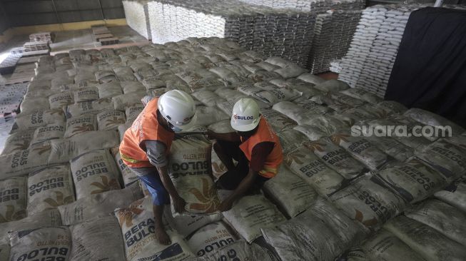 Pekerja menata karung berisi beras di Gudang Bulog Kanwil DKI dan Banten, Kelapa Gading, Jakarta, Kamis (18/3/2021). [Suara.com/Angga Budhiyanto]