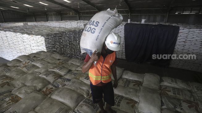 Pekerja mengangkut karung berisi beras di Gudang Bulog Kanwil DKI dan Banten, Kelapa Gading, Jakarta, Kamis (18/3/2021). [Suara.com/Angga Budhiyanto]